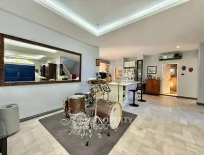 Spacious open-plan living area with modern kitchen and drum set, perfect for music enthusiasts.