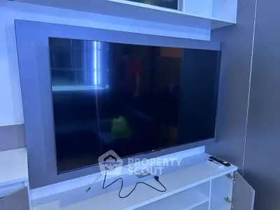 Modern living room with large flat-screen TV and sleek shelving unit.