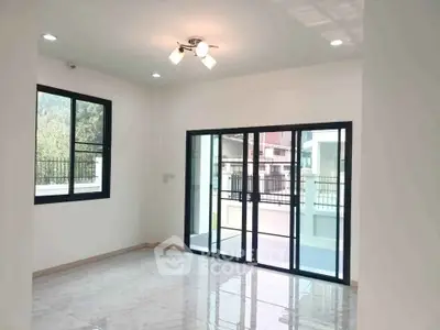 Spacious modern living room with large windows and sliding glass doors opening to a balcony.