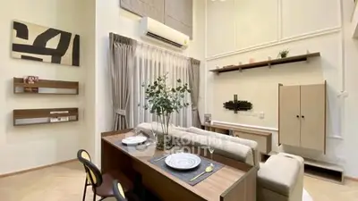 Modern living room with high ceilings and stylish decor, featuring a cozy dining area and elegant shelving.