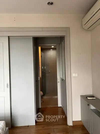 Modern apartment interior with sliding doors and air conditioning, featuring a glimpse into a sleek bathroom.