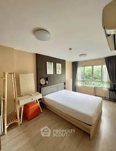 Spacious bedroom with modern decor and large window offering natural light.