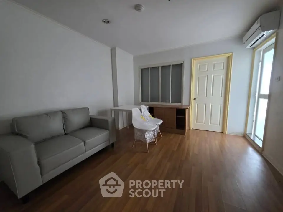 Spacious living room with modern sofa and wooden flooring in a bright apartment.