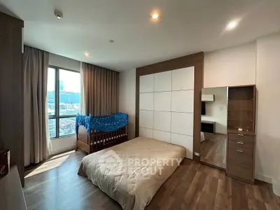 Spacious bedroom with city view, featuring modern furniture and large window for natural light.