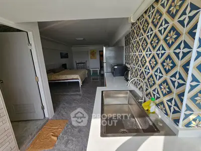 Stylish open-layout kitchen with modern sink and patterned backsplash in a cozy apartment.