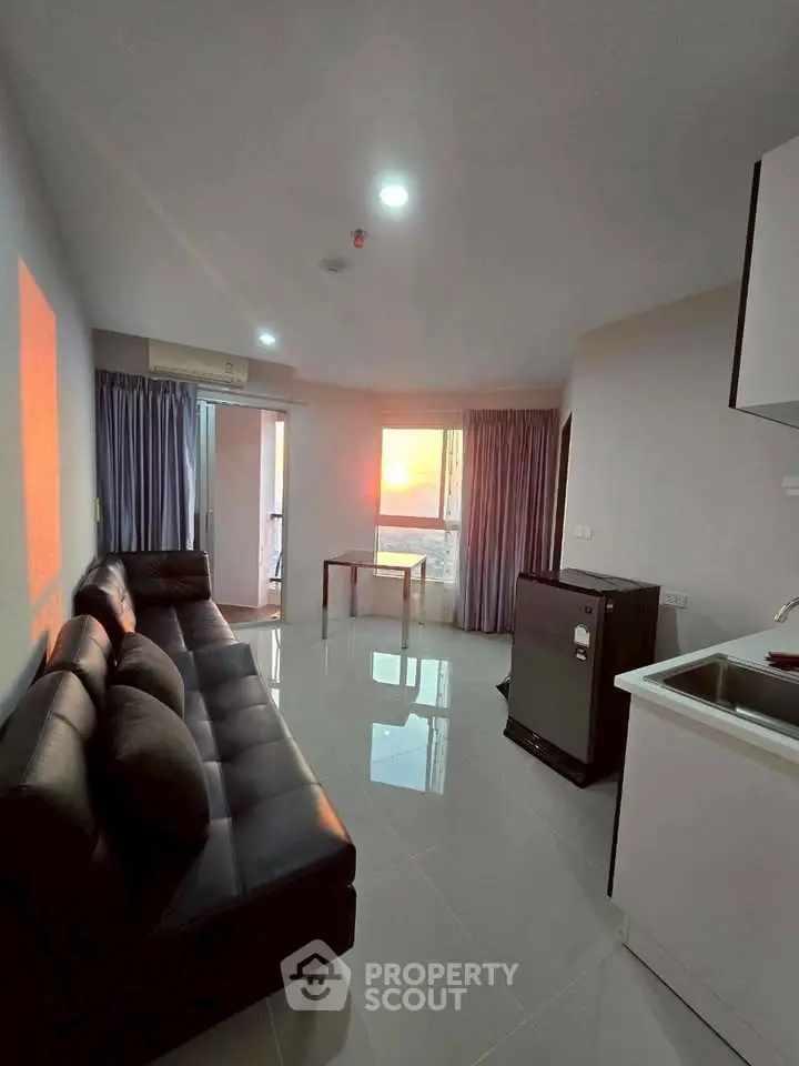 Modern living room with sleek black sofa and sunset view from window.