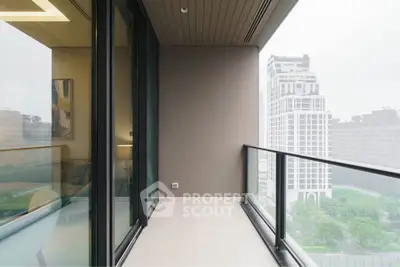 Spacious balcony with glass railing offering stunning city views in modern high-rise apartment.