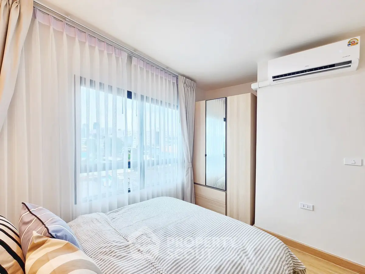 Bright and airy bedroom with large window and modern air conditioning unit.