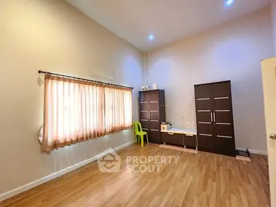 Spacious bedroom with wooden flooring and ample natural light