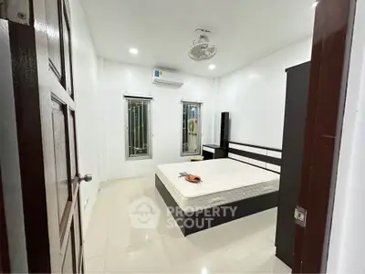 Spacious bedroom with modern furnishings and air conditioning in a bright, minimalist design.