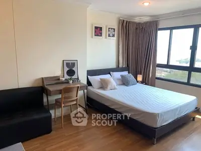 Modern bedroom with large window and cozy workspace in a stylish apartment.