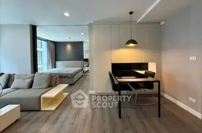 Modern open-plan living room with stylish dining area and cozy bedroom in a chic apartment.