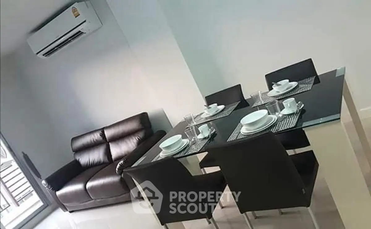 Modern dining area with sleek black chairs and a cozy leather sofa, perfect for stylish living.
