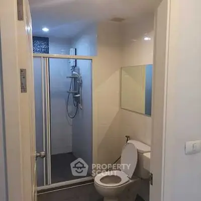 Modern bathroom with shower and toilet in a sleek apartment.