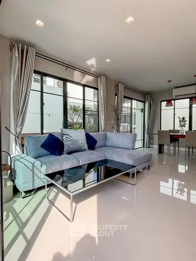 Spacious modern living room with large windows and elegant dining area