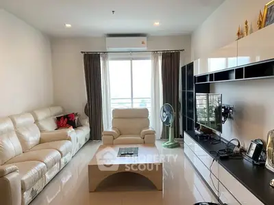 Spacious modern living room with leather sofas and large window view.