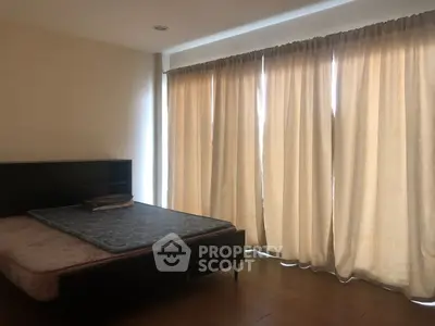 Spacious bedroom with large windows and elegant curtains, perfect for natural light lovers.