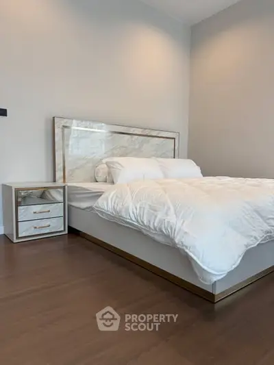 Modern bedroom with elegant bed and stylish nightstand on wooden floor.