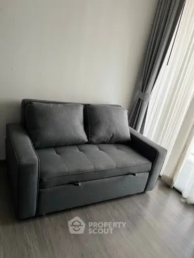 Modern gray sofa in a stylish living room with floor-to-ceiling curtains.