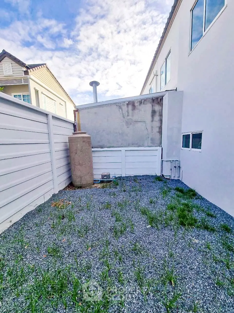 Spacious backyard with gravel and privacy fencing in modern residential area.