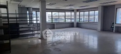 Spacious commercial office space with large windows and shelving units
