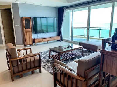 Luxurious living room with ocean view, modern furniture, and large windows opening to a spacious balcony.