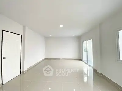 Spacious empty room with glossy tiled floor and large windows for natural light