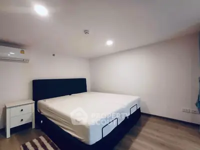 Spacious bedroom with modern design and ample lighting, featuring a comfortable bed and air conditioning.
