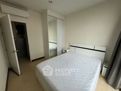 Modern minimalist bedroom with mirrored closet and air conditioning.