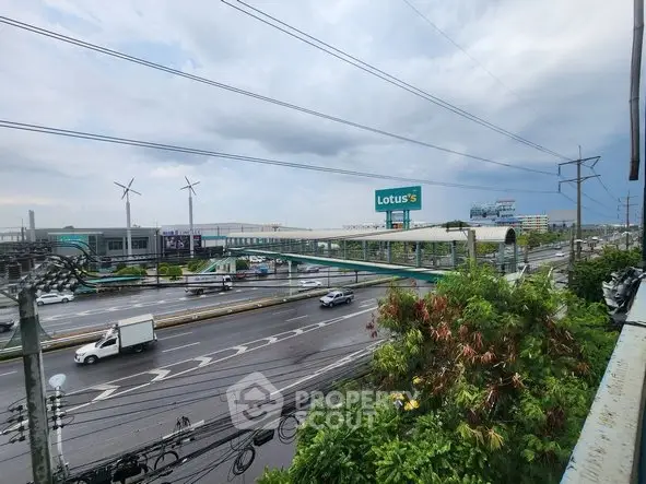 Scenic view of a bustling highway with a shopping center and wind turbines in the background.