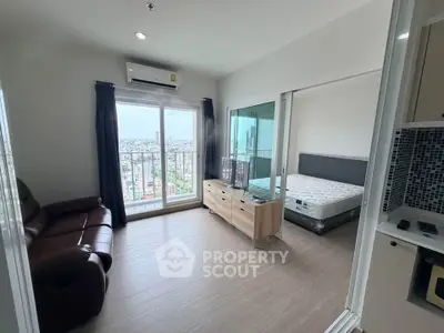 Modern apartment with balcony view, cozy living area, and adjacent bedroom in a high-rise building.
