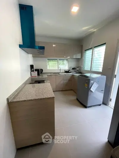 Modern kitchen with sleek cabinets, granite countertops, and large fridge in a bright, airy space.