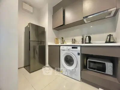 Modern kitchen with sleek appliances and washing machine in compact layout