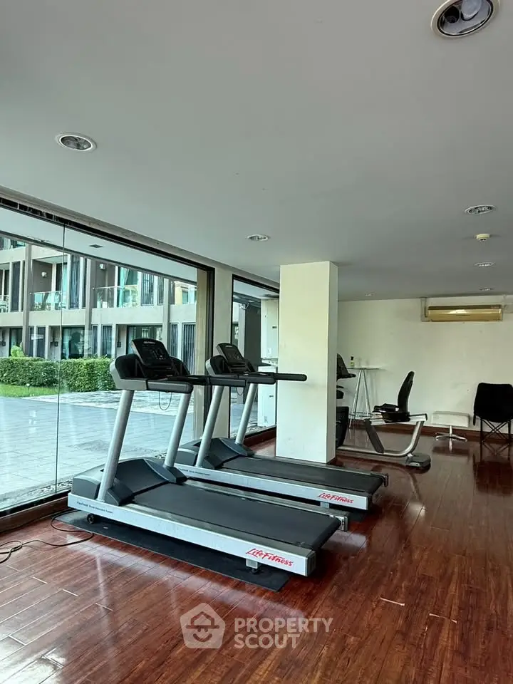 Modern gym with treadmills and large windows offering a scenic view, perfect for fitness enthusiasts.