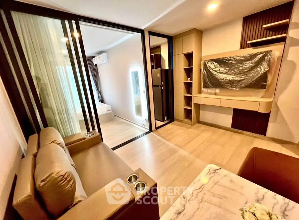 Modern living room with sleek design and sliding glass doors leading to a cozy bedroom.