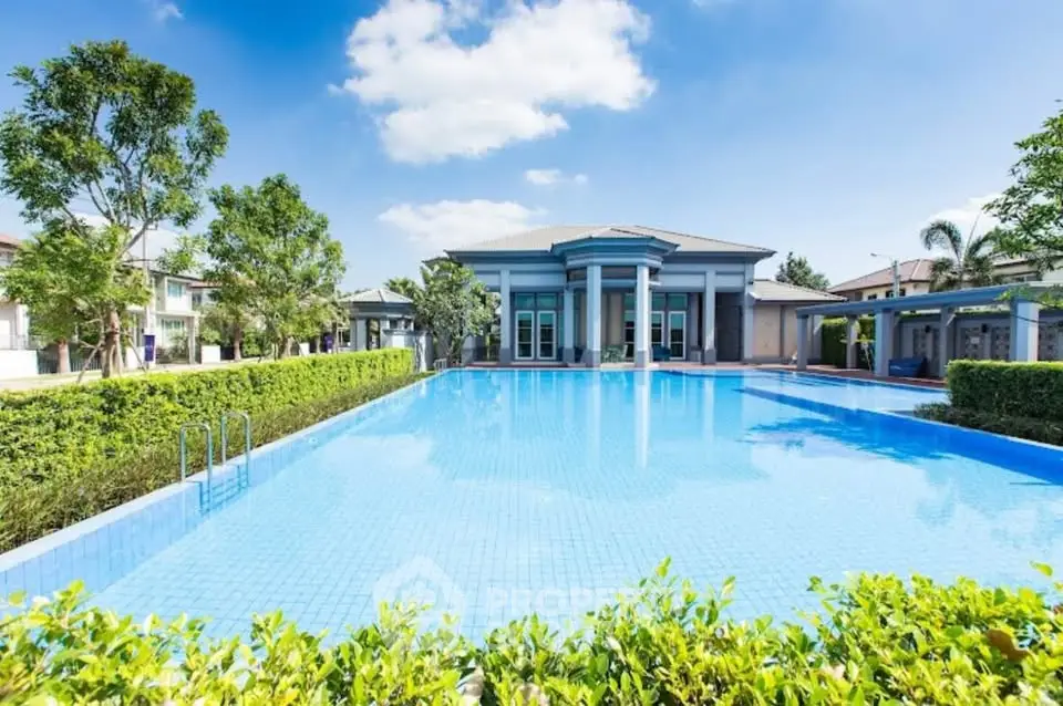 Luxurious residential complex with stunning pool and lush greenery under clear blue sky.