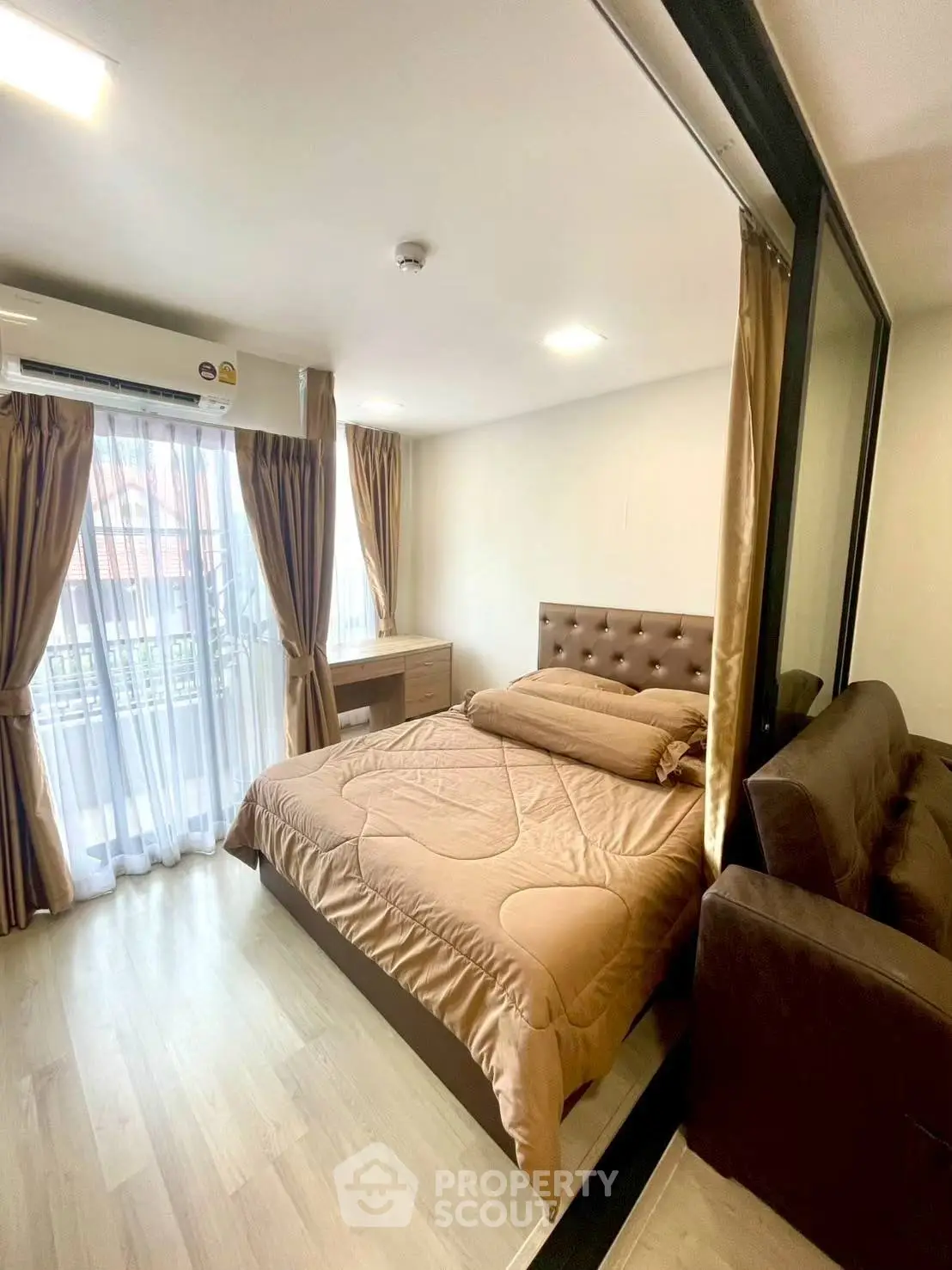 Cozy bedroom with modern decor, large window, and stylish furnishings in a well-lit apartment.