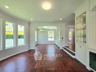 Spacious living room with elegant hardwood floors and built-in cabinetry, featuring abundant natural light.