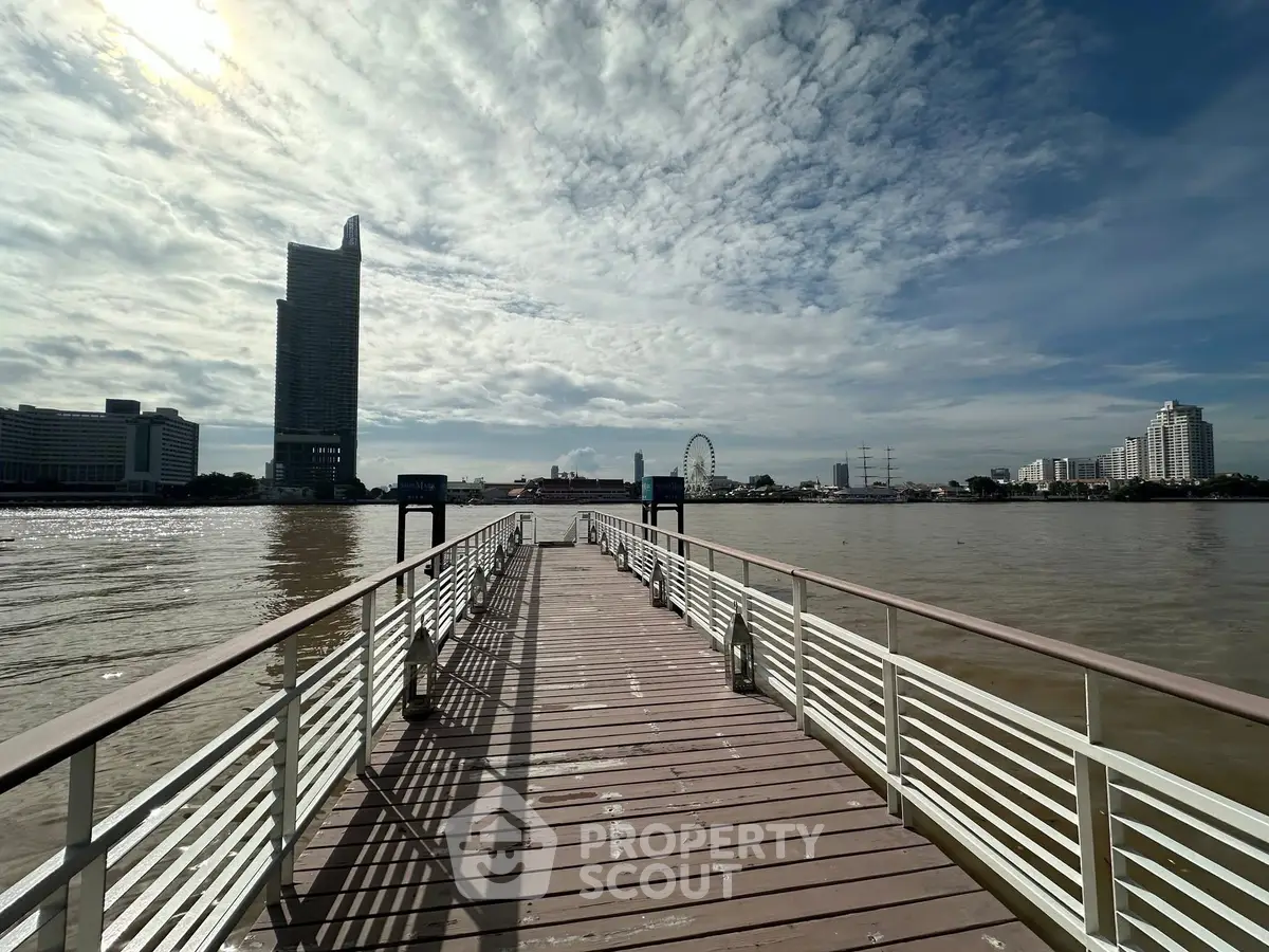 Scenic riverside view with modern skyscraper and ferris wheel in the background, perfect for urban living.