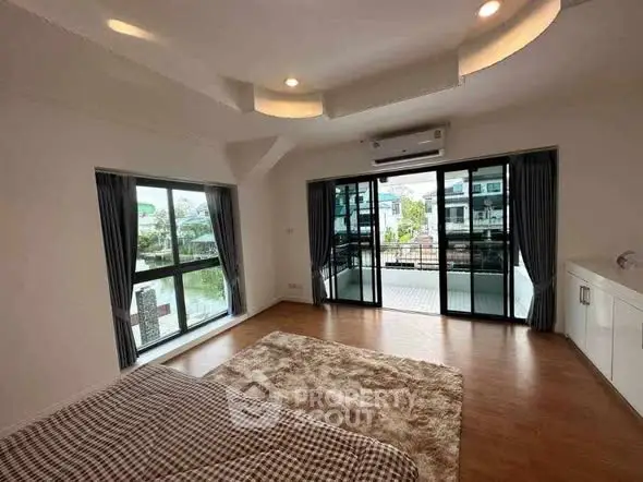 Spacious bedroom with large windows and balcony access in modern home.