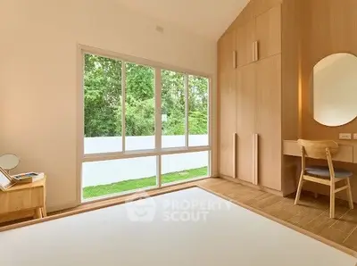 Spacious bedroom with large window and built-in wooden wardrobe