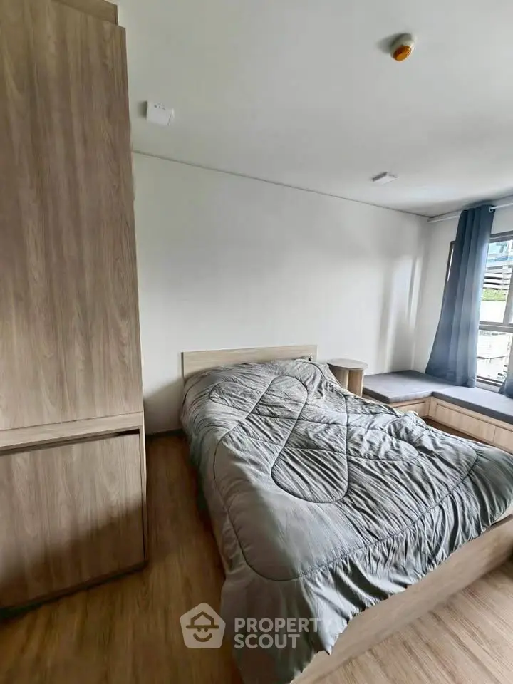 Cozy bedroom with modern wooden furniture and large window for natural light.