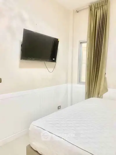 Modern bedroom with wall-mounted TV and elegant curtains, perfect for cozy living.