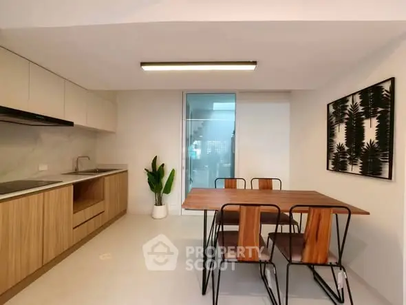 Modern kitchen with wooden cabinets and dining area featuring a stylish table and chairs, perfect for contemporary living.