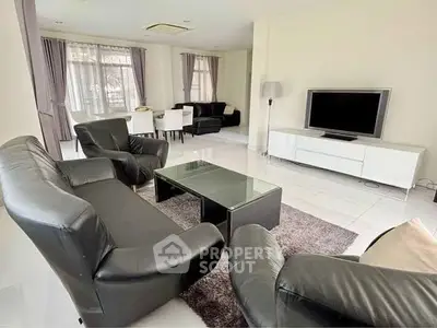 Spacious living room with modern black leather sofas and flat-screen TV