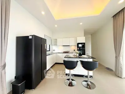 Modern kitchen with sleek black appliances and stylish bar stools in a bright open layout.