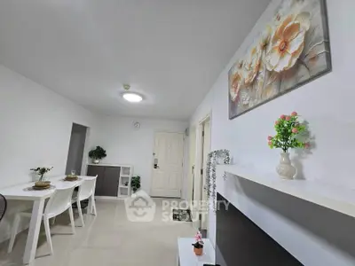 Modern living room with elegant decor and dining area, featuring white furniture and floral artwork.