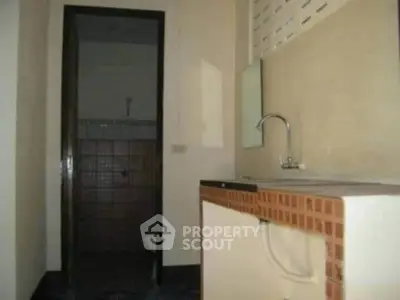 Compact kitchen area with tiled countertop and sink