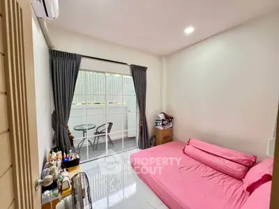 Cozy bedroom with pink bedding and balcony access, featuring modern decor and natural light.