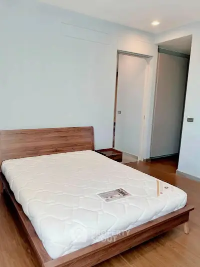 Spacious bedroom with wooden bed frame and modern design in a stylish apartment.